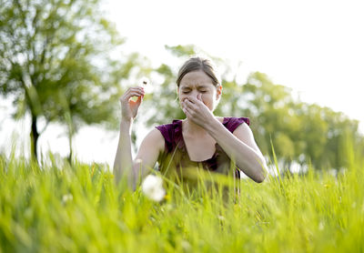 Woman sneezing on grassy field