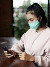 Woman using mobile phone while sitting on table