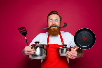 Portrait of man holding ice cream against red background