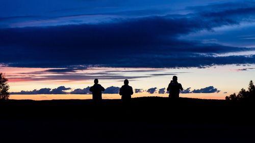 Silhouette people on field against sky during sunset