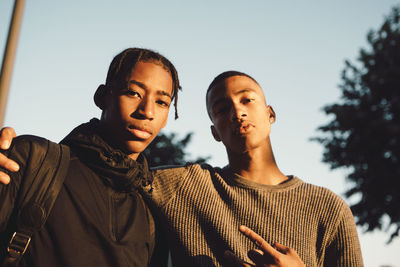 Low angle portrait of confident friends standing in city during sunset