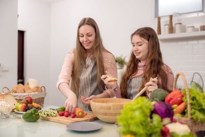 Happy friends and fruits on table at home