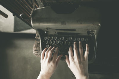 Cropped hands of person typing on typewriter