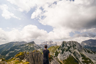 Rear view of man standing on rock against sky