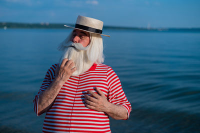 Woman wearing hat standing by sea