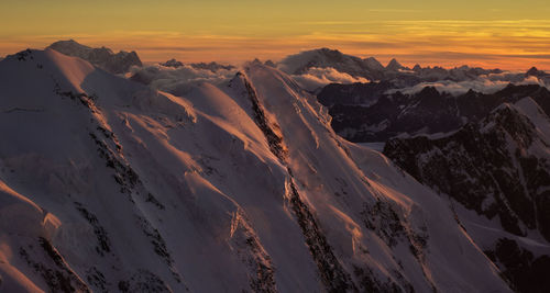 Scenic view of snow covered mountains against sky during sunset