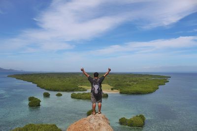 Rear view of person standing by sea against sky