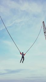 Low angle view of man bungee jumping against sky