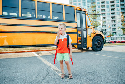 Smiling boy standing by bus