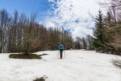 Rear view of man walking on snow covered landscape