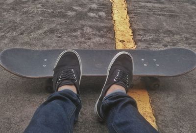 Low section of man skateboarding on road