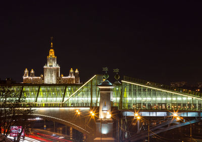 Illuminated bridge over river against sky at night