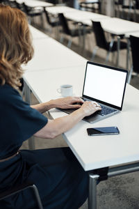 Female entrepreneur typing on laptop in board room at office