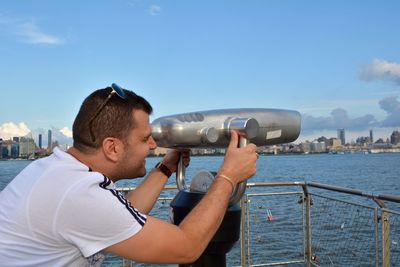 Man looking at sea through coin-operated binoculars