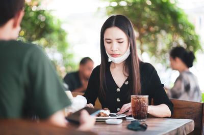 Young woman using phone while sitting on table