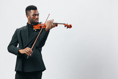 Young woman holding violin against white background