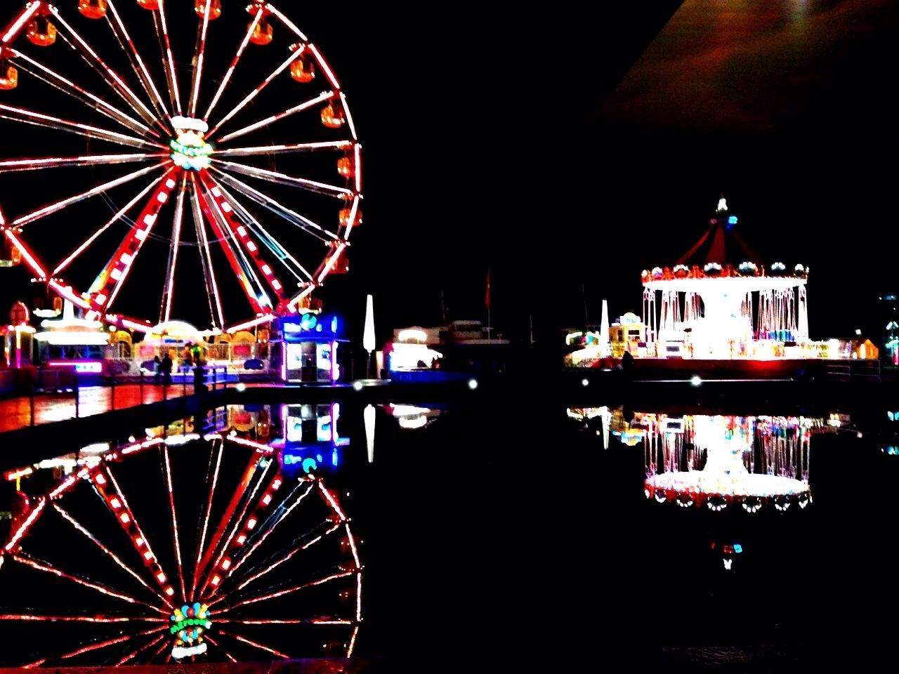 amusement park, amusement park ride, ferris wheel, arts culture and entertainment, illuminated, night, sky, travel, built structure, travel destinations, clear sky, water, multi colored, transportation, architecture, tourism, outdoors, low angle view, famous place, big wheel