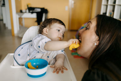 Baby boy feeding mother at home