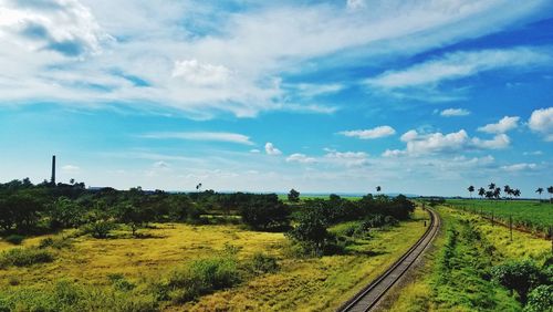 Panoramic shot of railroad tracks on field against sky
