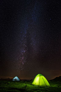 Illuminated tents on field against star field