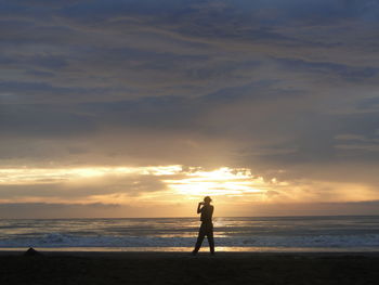 Silhouette of people on beach at sunset