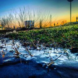 Surface level of wet land against sky during sunset