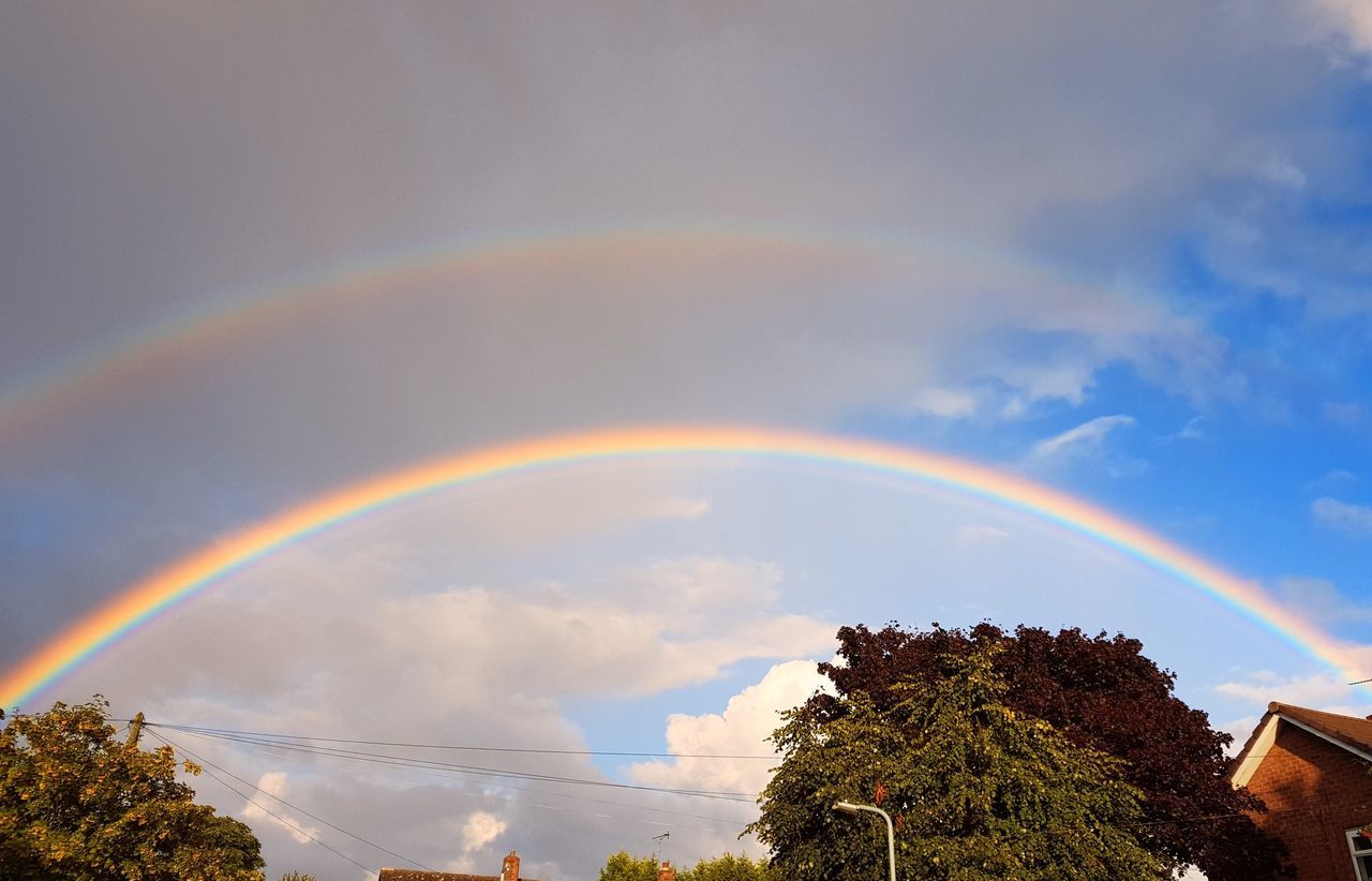 rainbow, sky, double rainbow, tree, cloud, plant, beauty in nature, multi colored, nature, scenics - nature, architecture, building exterior, no people, sunlight, built structure, tranquility, spectrum, idyllic, natural phenomenon, low angle view, outdoors, environment, day, building, landscape, tranquil scene, house, city, rain