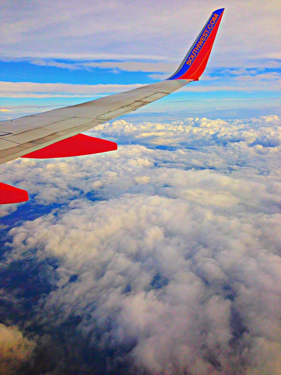 flying, transportation, aircraft wing, sky, mid-air, air vehicle, cloud - sky, airplane, mode of transport, part of, cropped, nature, scenics, beauty in nature, travel, flag, cloud, tranquility, tranquil scene, day