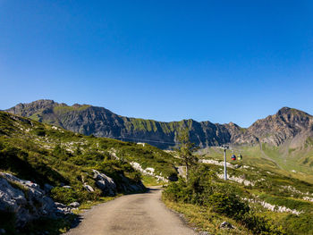 Road amidst mountains against clear blue sky