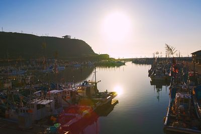 Boats moored at harbor against clear sky during sunset