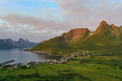 Mountain peaks and a small coastal village during sunset in senja island, norway