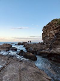 Rock formations on shore against sky