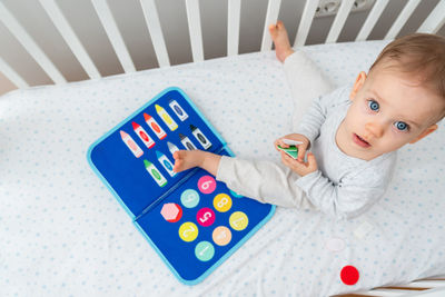 High angle view of cute baby boy lying on bed at home