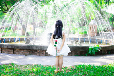 Woman standing by plants against trees