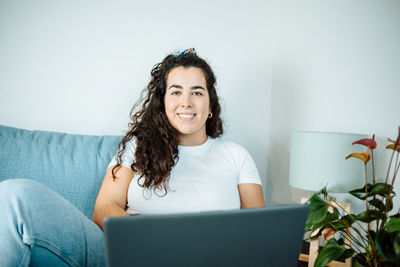 Portrait of young woman sitting on sofa at home