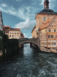 Arch bridge over river amidst buildings against sky