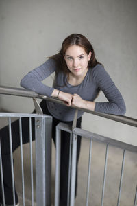 High angle view portrait of woman standing by railing on staircase