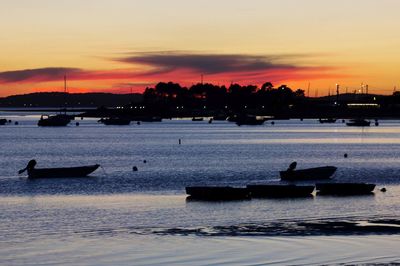 Silhouette boats in sea against sky during sunset