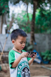 Boy holding mobile phone outdoors