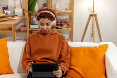 Young woman using mobile phone while sitting on sofa at home