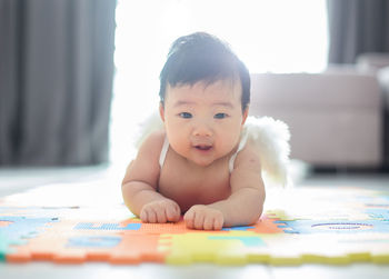 Portrait of cute baby boy wearing costume wing while lying at home