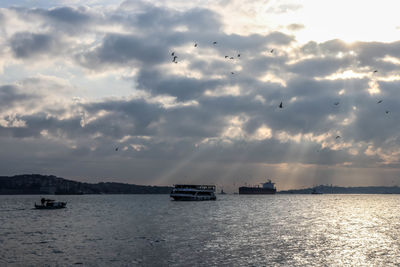 Boats sailing in sea against sky during sunset