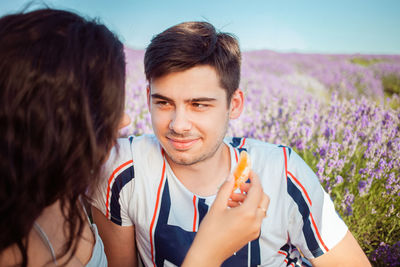 A young girl and a guy feed each other an orange