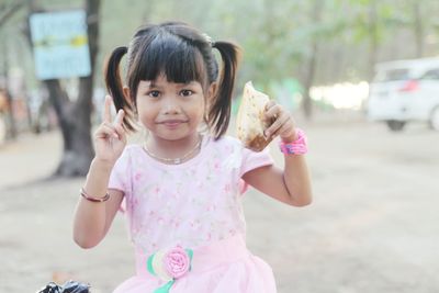 Portrait of cute girl holding food packet outdoors