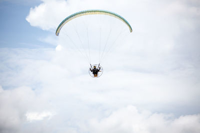 Low angle view of person paragliding against sky