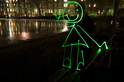 Illuminated road sign in city at night