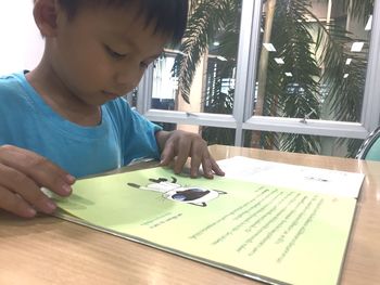 High angle view of boy looking at camera on table