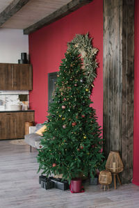 Stylish christmas tree with gifts under it in a living room with burgundy walls