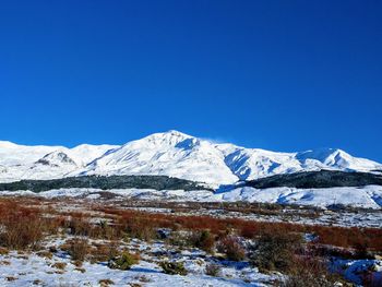 Scenic view of snowcapped mountains against clear blue sky