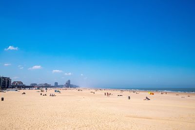 People at beach against blue sky